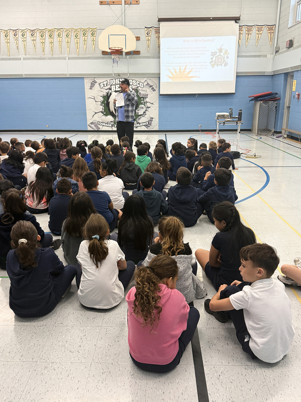 Photo of St. John Bosco students listening to Jason speak during the visit