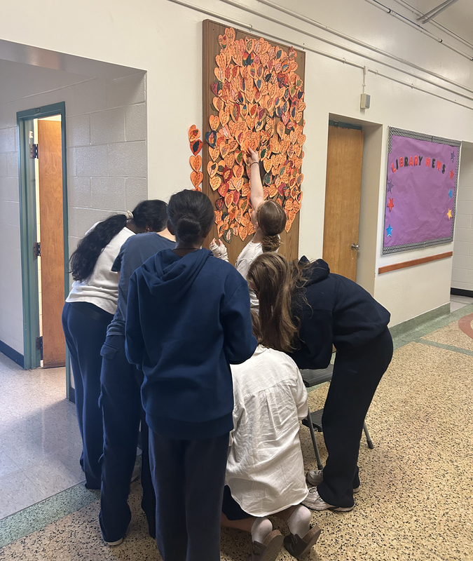 Photo of St. Cecilia students posting up hearts into the collaborative Tree of Life display