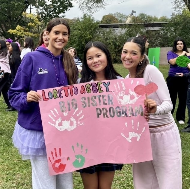 Photo of three students dressed casually, with a sign that says Loretty Abbey Big Sister Program