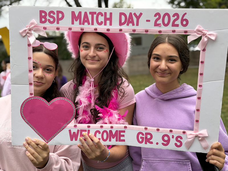 Students dressed in pink and purple pose through a crafted white and pink frame that says BSP Match Day - 2026 - Welcome Grade 9s
