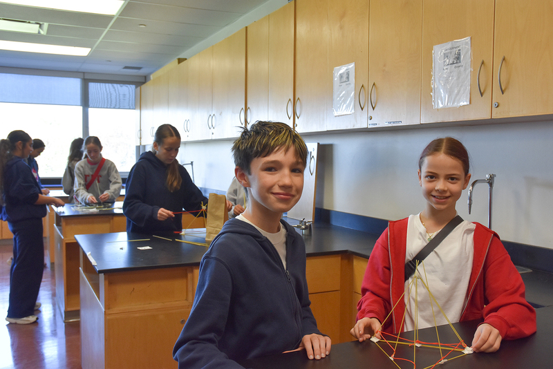 Photo of elementary student visitors in a science classroom doing a scientific activity together at the work stations in small groups