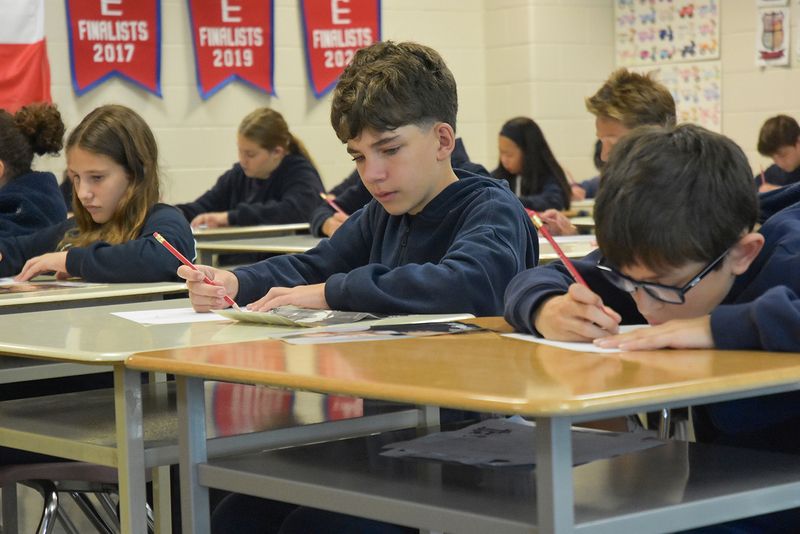 Photo of elementary student visitors sitting in a classroom doing a creative activity together