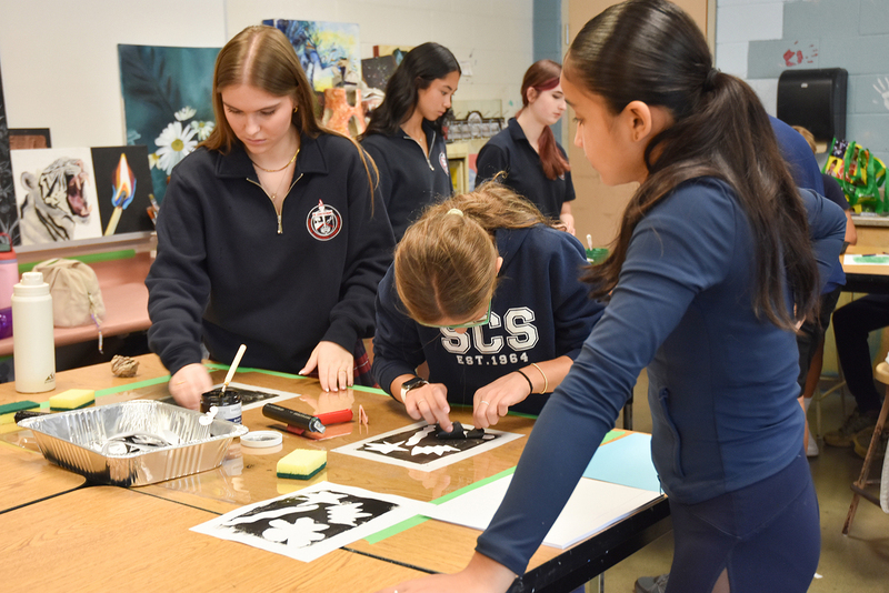 Photo of elementary student visitors in a classroom doing an art activity together in groups while guided by Redmond students