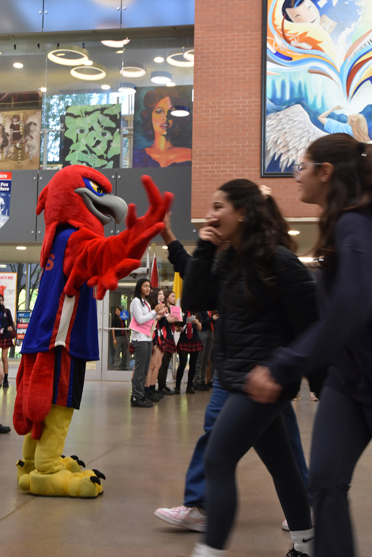Photo of elementary student visitors being greeted by the Redmond red bird mascot in costume at the festival