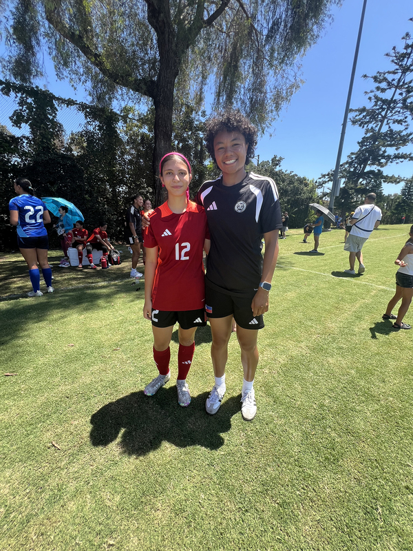 Photo of Olivia on the coat in her red jersey with the number 12 on it in white, posing with another player