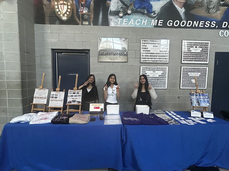 Photo of three FHC students standing behind one of the Club presentation tables