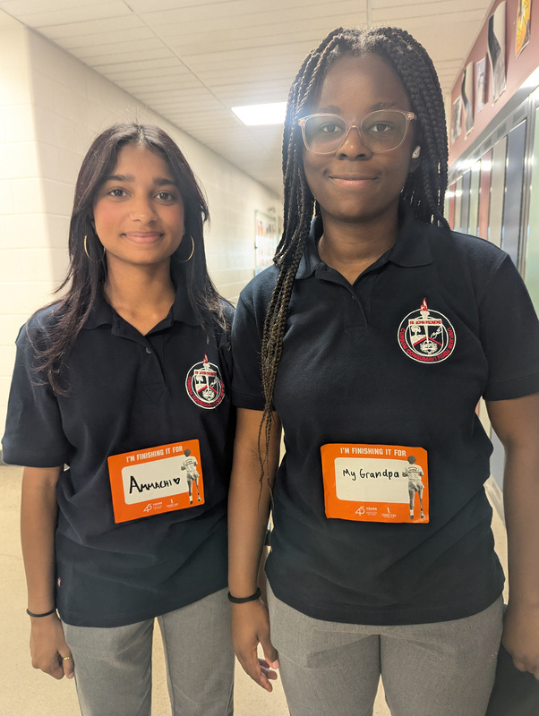 Photo of two students about to go on the walk, with names on their shirt saying who they are finishing the walk for