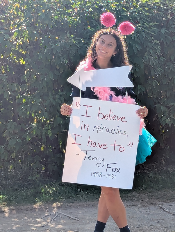 A guide along the walk holding a sign that says "I believe in miracles; I have to." by Terry Fox 1958-1981