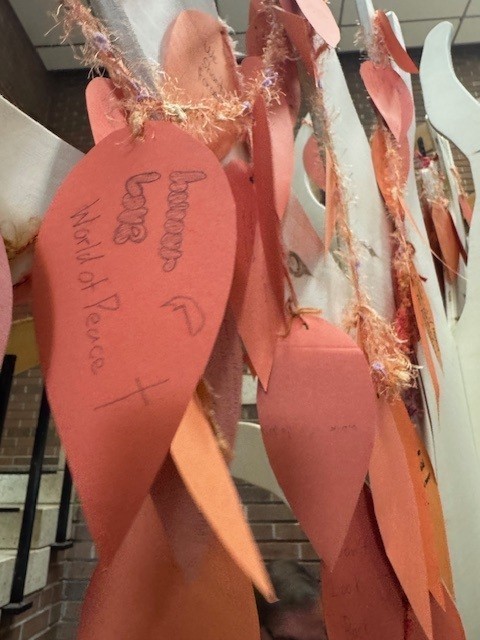 Closeup photos of leaves on the tree that have students' messages written on them