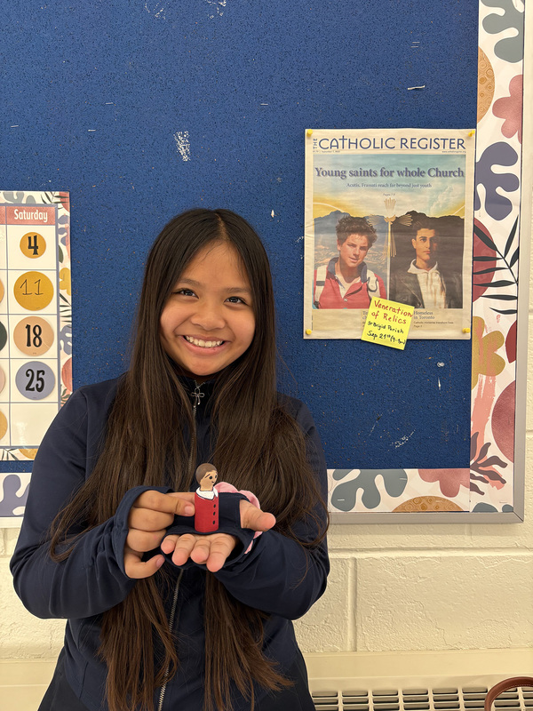 Photo of a student holding up a figurine of a saintly figure