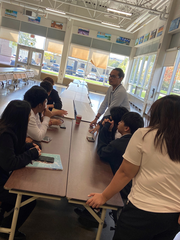 Photo of JCM staff and new English Language Learner students conversing together at the Meet-and-Greet