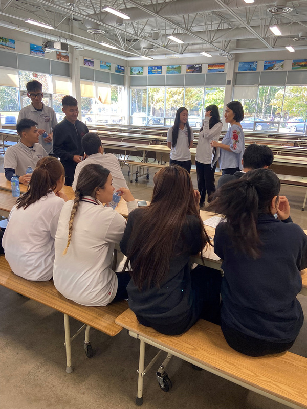 Photo of JCM staff and new English Language Learner students conversing together at the Meet-and-Greet