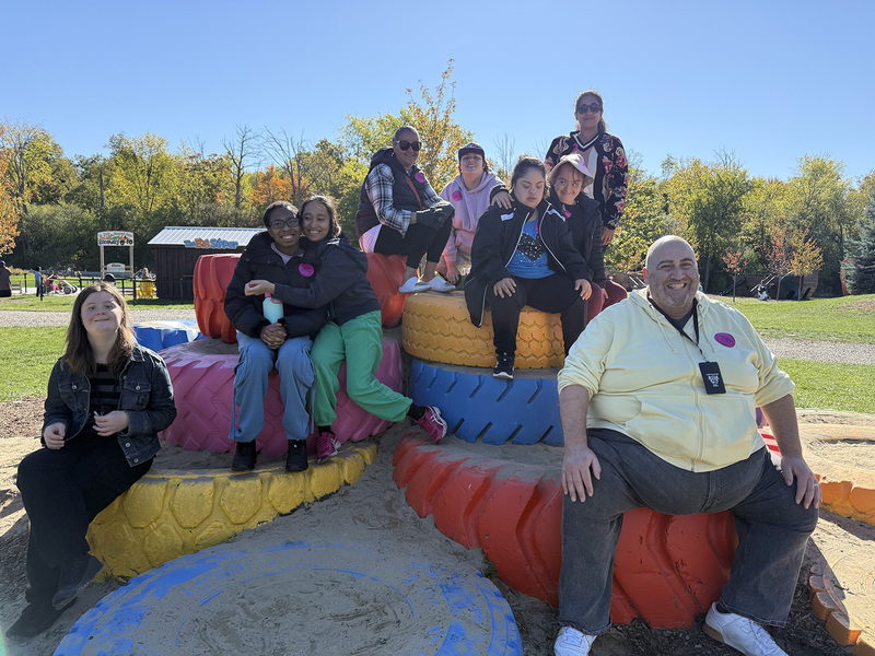 Group photo of Loretto College School students and staff sitting on a platform made of painted old tires