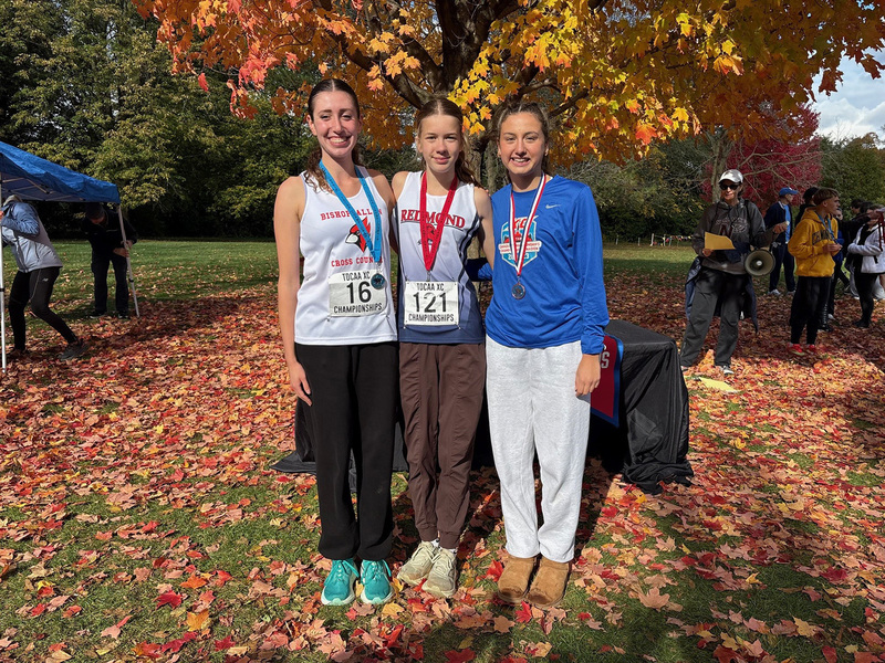 Group photo of three cross country runners with their winning medals