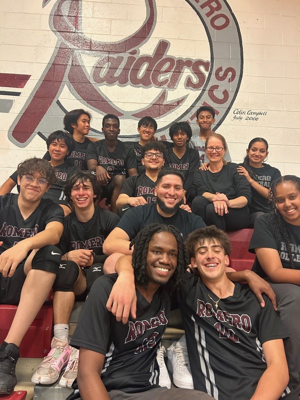 Group photo of students in athletic wear, posing on bleachers.