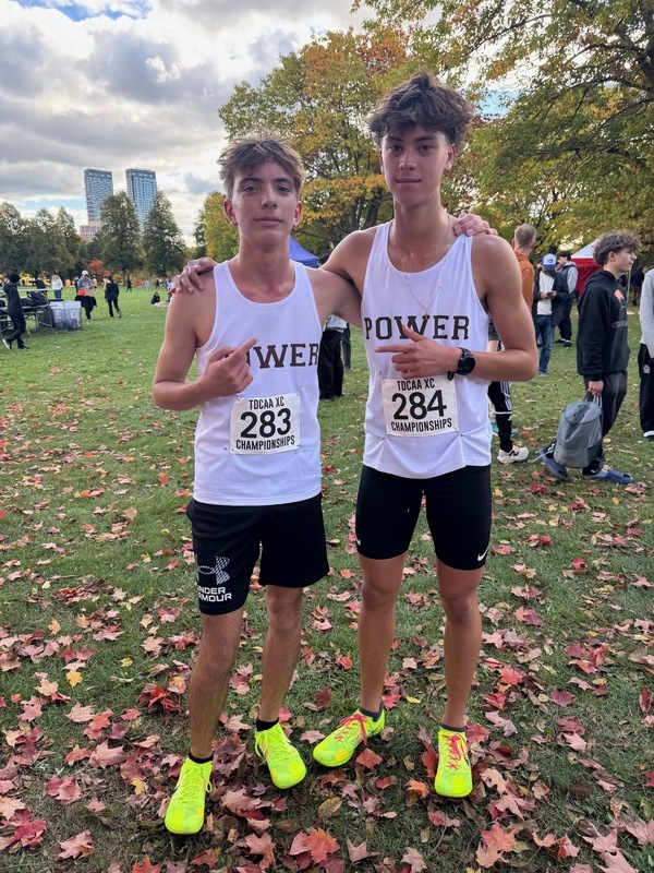 2 students posing outdoors in running uniform