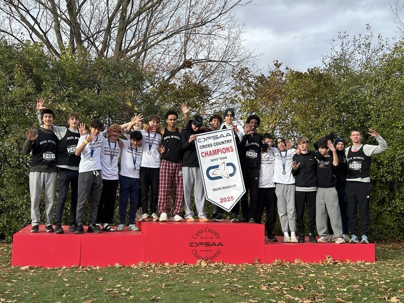 Group photo of the Neil McNeil Boys Cross Country Team with their championship medals and banner