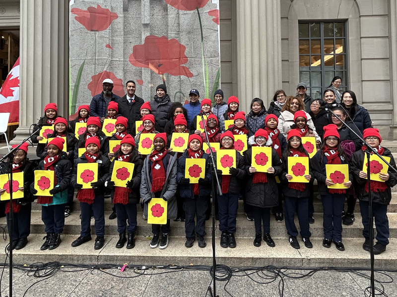 Group photo of Our Lady of Lourdes students with poppy props, along with TCDSB staff and Manulife personnel