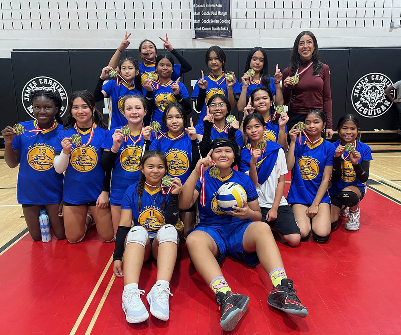 Group photo of St. Margaret Girls Volleyball Team with their Coach, in their team jerseys and showing off their medals