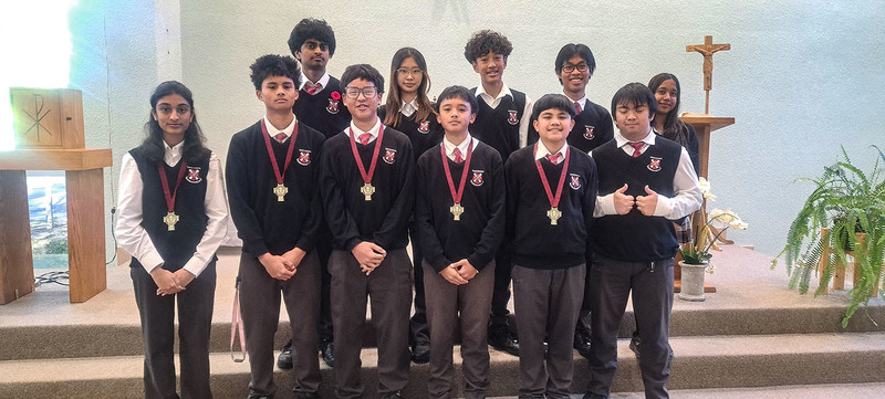 Photo of St. Patrick alter server students standing in front of the alter in their school uniform and wearing their medals