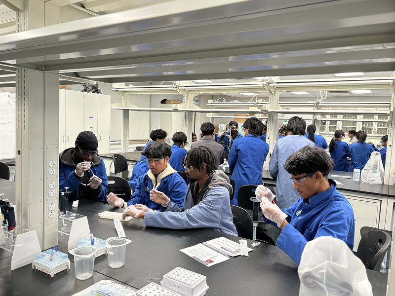 Photo of SJOA students working in a Toronto Metropolitan University (TMU) lab with the help of TMU students during the event