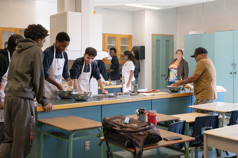 Photo of Chef Roger Mooking teaching Father Henry Carr students -prepare a balanced meal from scratch: saltfish buljol and roast bake