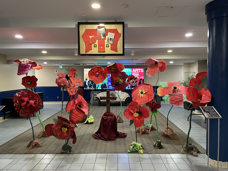 Photo of a sculpture installation created by Cardinal Carter students, showing a field of giant poppies along with memorial and informative plaques.