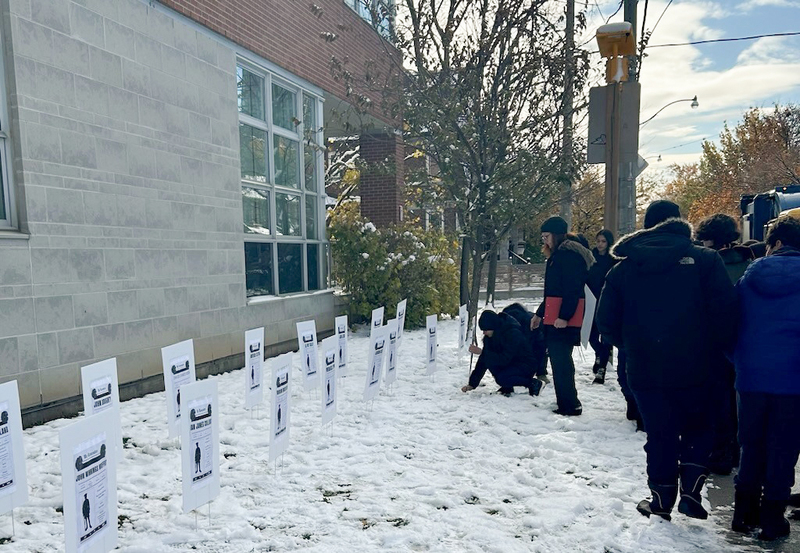 Photo of St. Anthony students planting informative plaques in the ground for Remembrance Day
