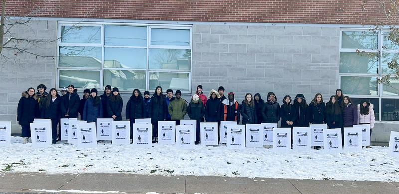 Photo of St. Anthony students posing with the informative plaques they planted in the school grounds for Remembrance Day
