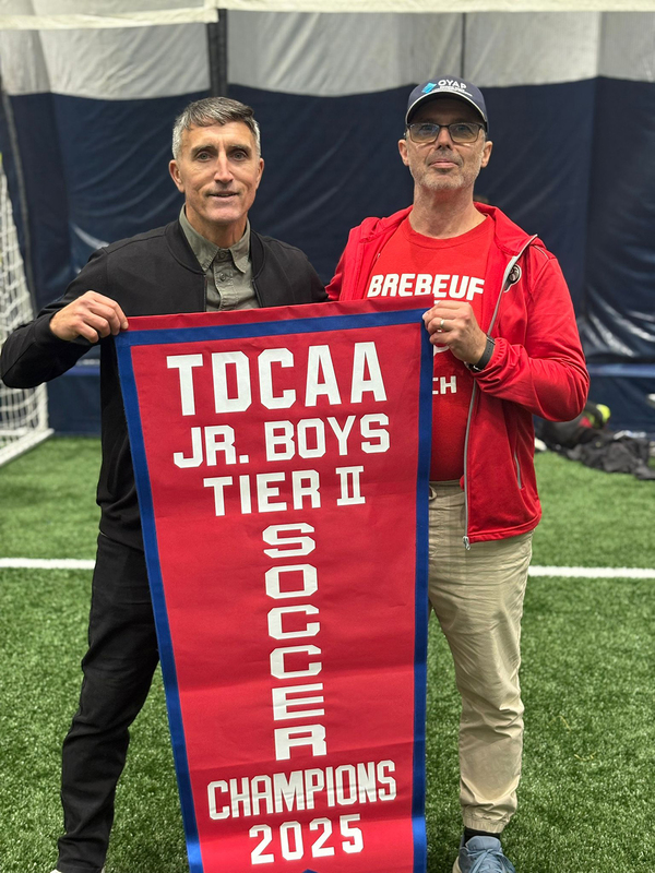 Photo of Brebeuf coaching staff with the TDCAA championship banner