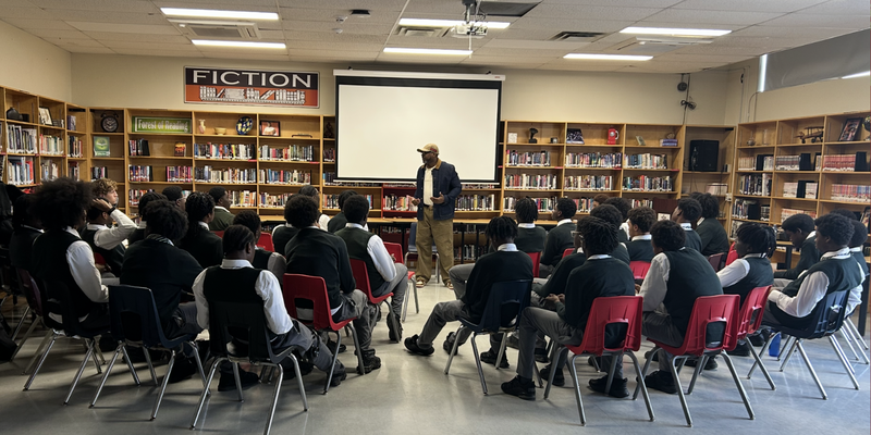 Students sitting in a library facing a speaker.