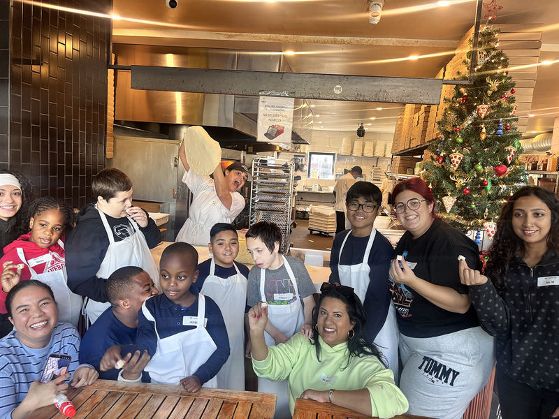Group photo of Santa Maria students and staff making pizza with North of Brooklyn Pizzeria staff