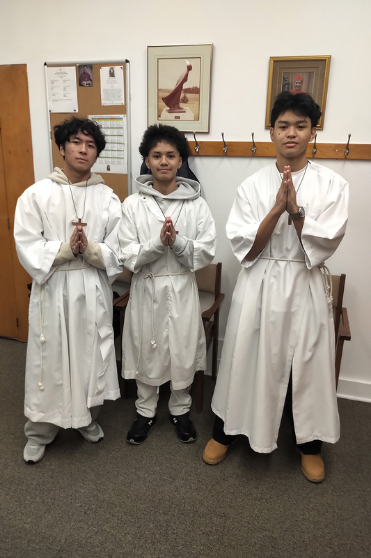 Photo of three SJOA students praying in robes