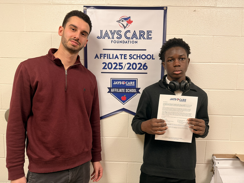 Photo of JCM staff member and student together with a banner behind them announcing the affiliation