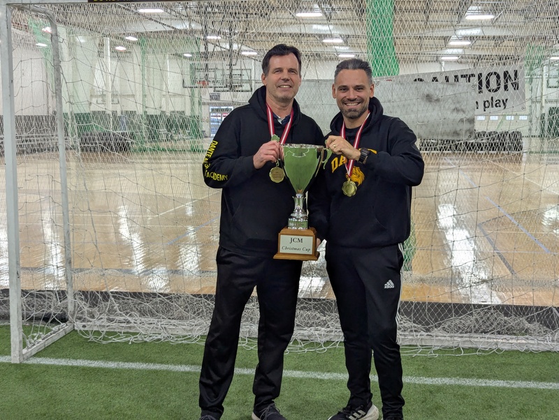 soccer coaches posing with gold medal trophy