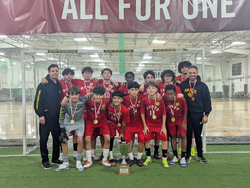 Soccer team posing on an indoor field with coaches. 