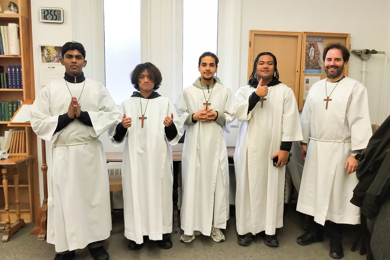 Photo of four SJOA students as altar servers during Mass at Our Lady of Lourdes parish