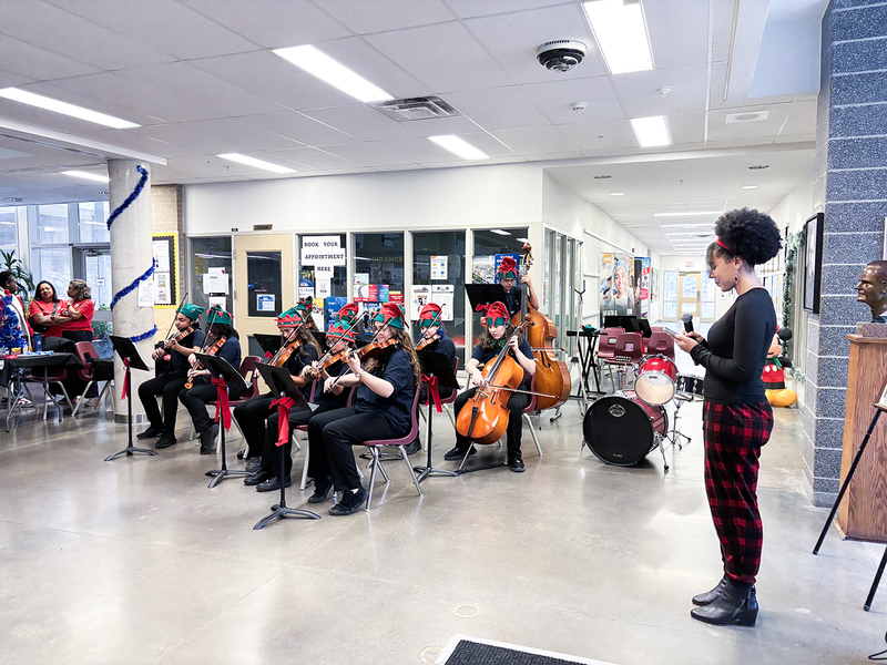 Photo of Monsignor Percy Johnson music students performing with strings instruments at the market