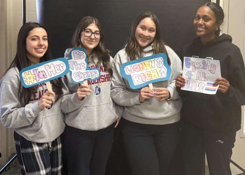 Photo of four Madonna students holding up signs they created