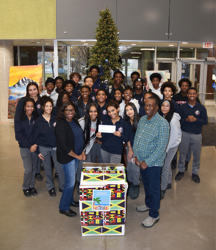 Group photo of Redmond students and The Jamaican Canadian Society representatives with the boxes of food and supplies collected and the cheque