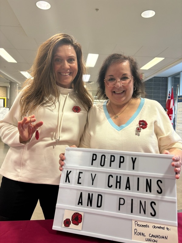 Photo of the MPJ staff holding up a sign advertising poppy key chains and pins