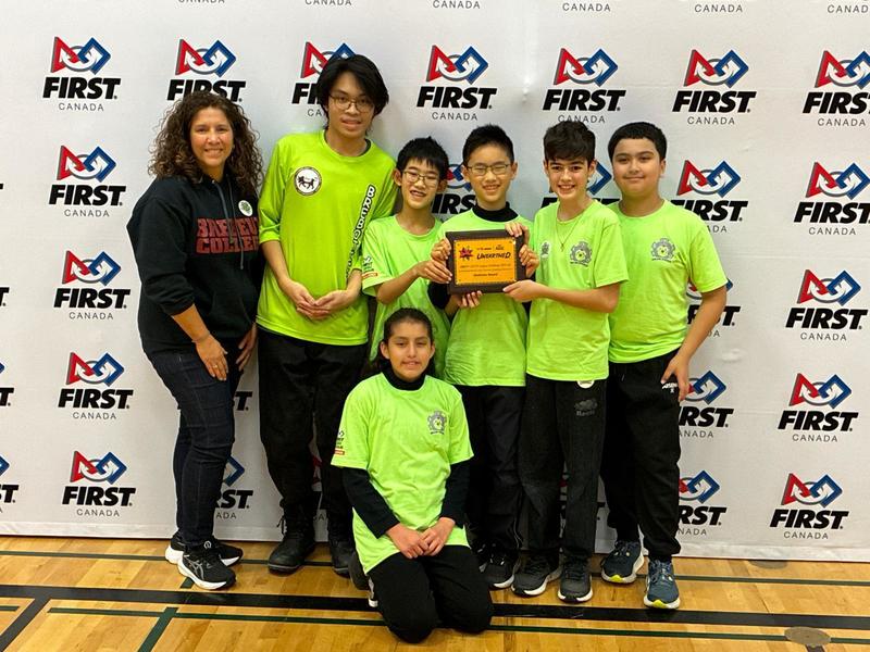 Group photo of robotics team with their award and teacher