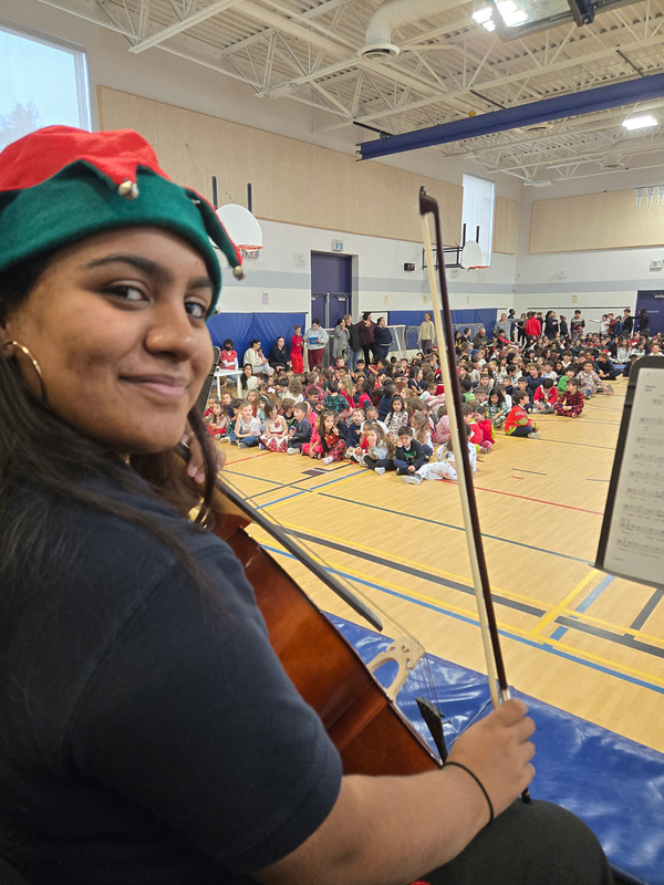 Photo of MPJ Strings students with their instruments and Christmas hats, ready to perform to the elementary students
