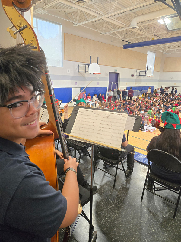 Photo of MPJ Strings students with their instruments and Christmas hats, ready to perform to the elementary students