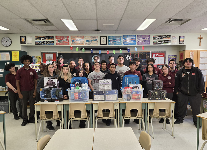 Group photo of St. Oscar Romero students in a classroom with the items that they have collected to donate
