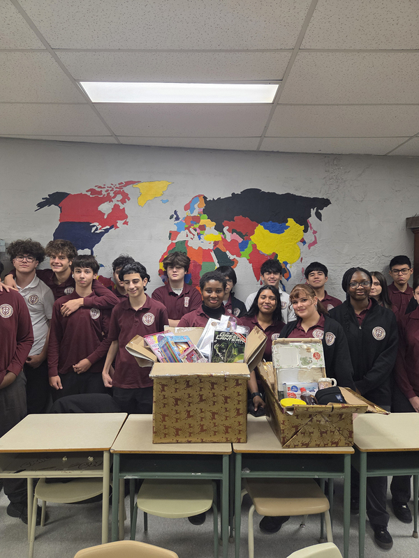 Group photo of St. Oscar Romero students in a classroom with the items that they have collected to donate