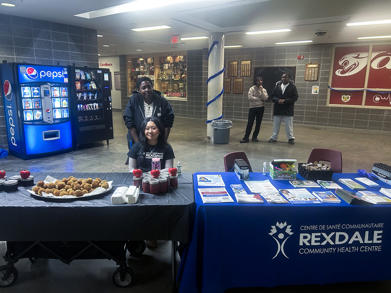 Photo of two MPJ students at the Rooted and Rising event in charge of an information table