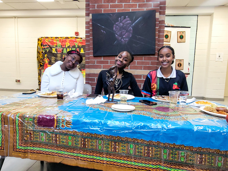 Photo of three students eating food together at the celebration
