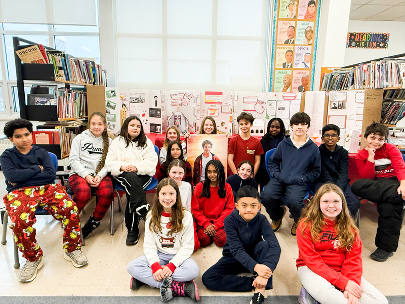 Photo of St. Benedict students in the classroom with their works displayed behind them