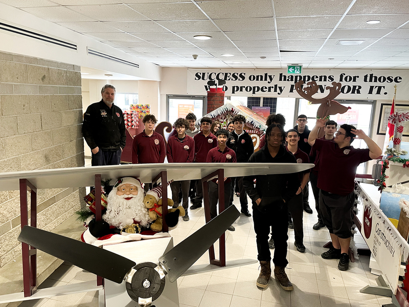 Photo of a constructed airplace with Santa in it, with St. Oscar Romero students standing behind the display